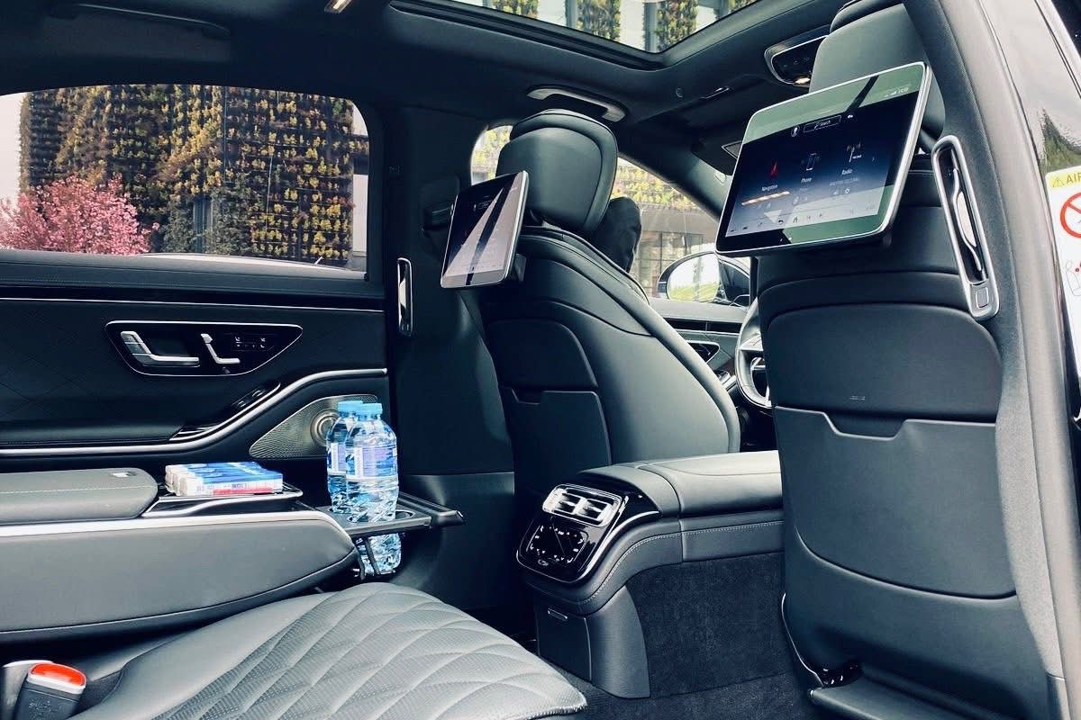 Mercedes S-Class-ის უკანა სალონის ინტერიერი: კრემისფერი ტყავი, უკანა სავარძლის ეკრანი, ცის სარკმელი და ფონის განათება.