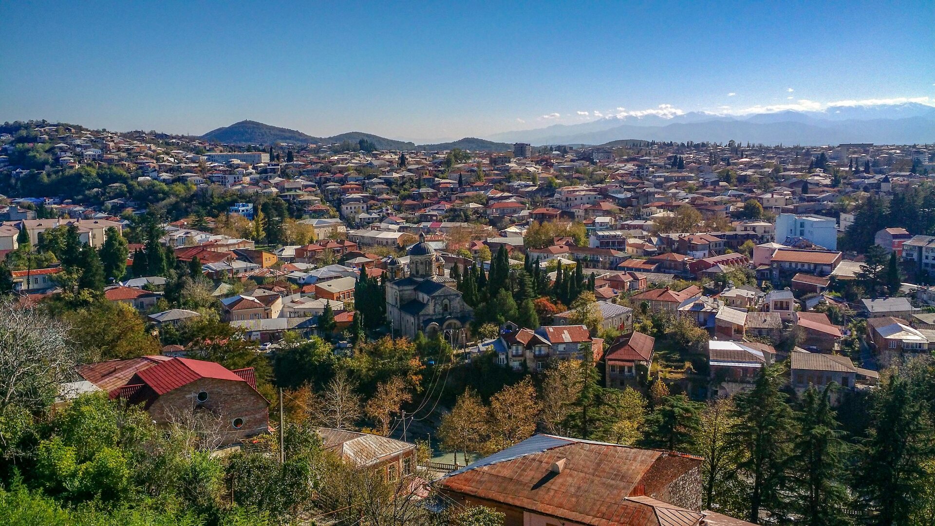 ქუთაისის ხედი ბაგრატის ტაძრის მთიდან: ქალაქი გადაშლილია მცენარეებში, რიონის მდინარის ხეობაში.