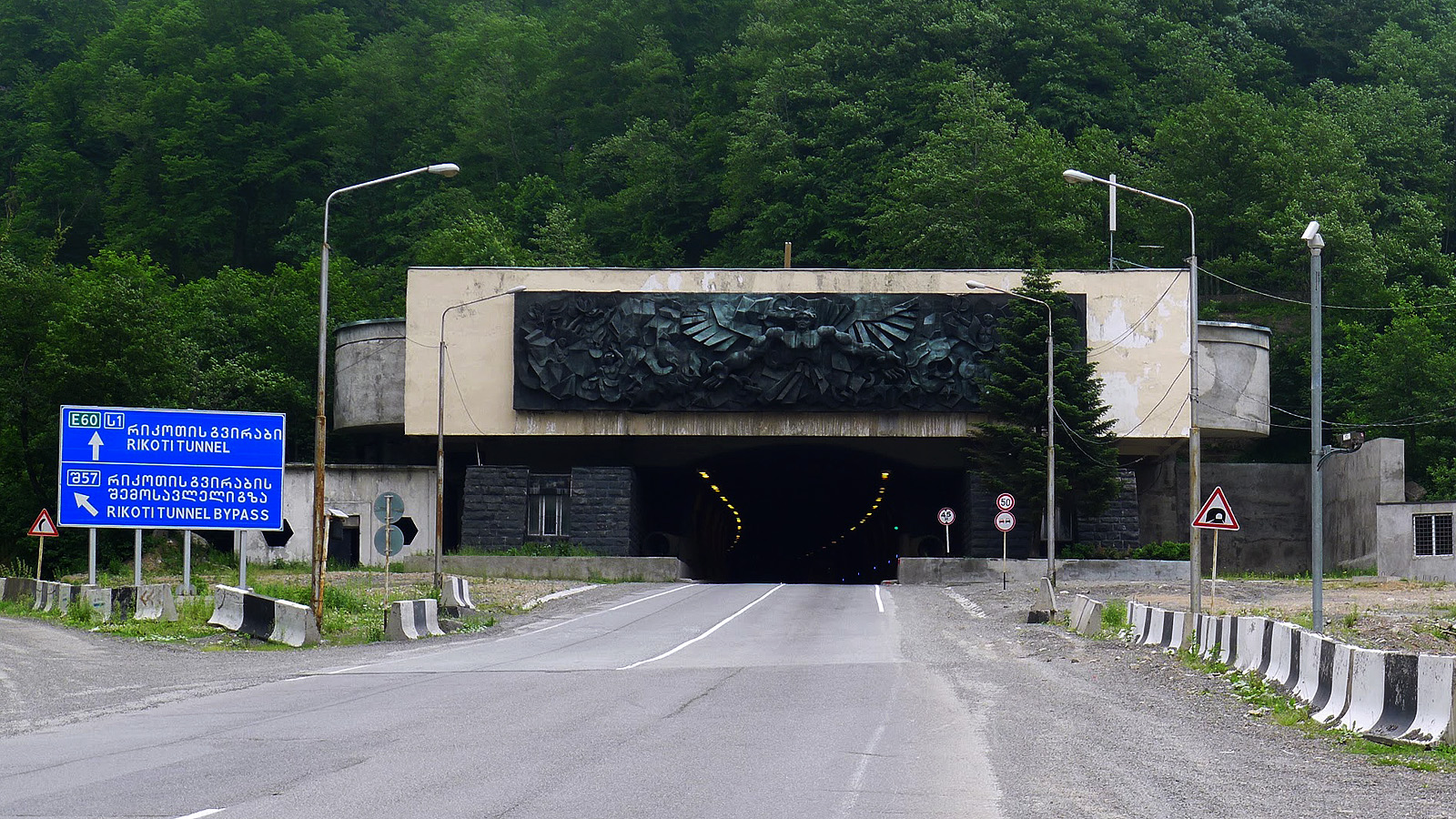 რიკოთის გვირაბის ჩრდილოეთ შესასვლელი საქართველოს მოდერნიზებულ აღმოსავლეთ-დასავლეთის მაგისტრალზე, ახალი პორტალი ჭრის გადაჭრის მწვანე ტყიან მთის ფერდობს.