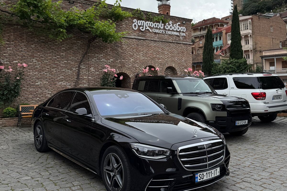 შავი Mercedes S-Class ჯდება გულოს თერმული სპას შესასვლელთან ძველი თბილისის აბანოთუბანის უბანში.