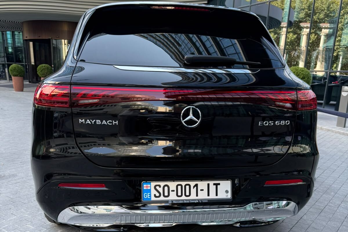 შავი Mercedes-Maybach EQS 680 უკნიდან, საბარგულზე MAYBACH და EQS 680 ნიშნებით, თბილისში, შენობის შესასვლელთან.