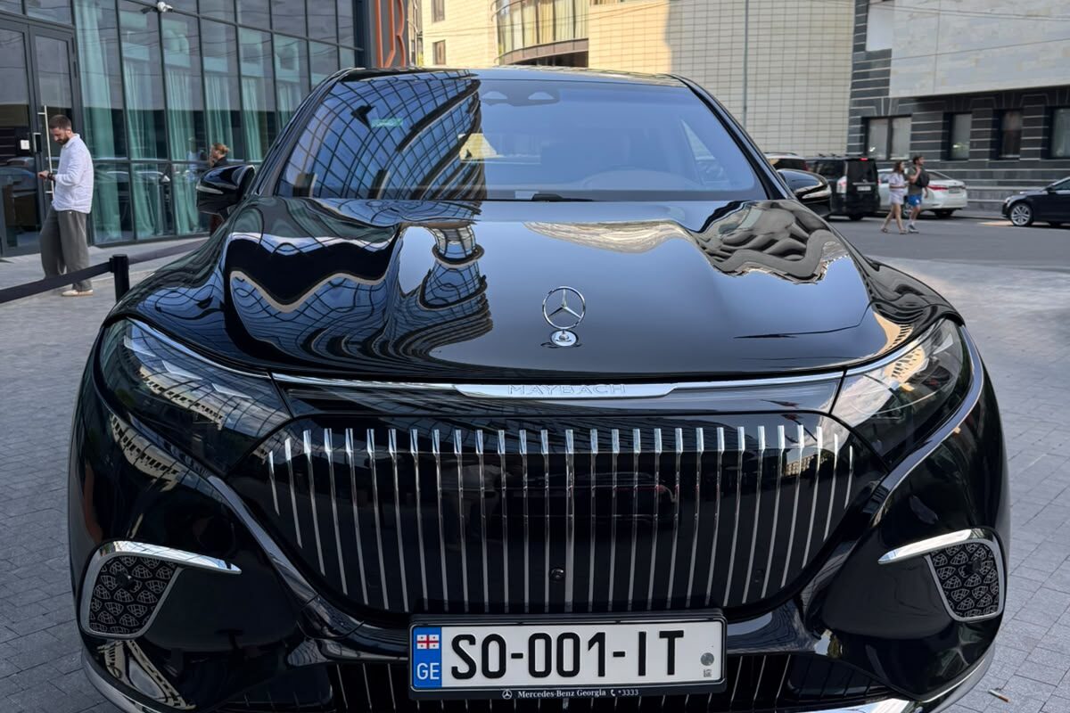 შავი Mercedes-Maybach EQS 680 ქართული ნომრით, წინიდან, თბილისში, ქვაფენილზე, საოფისე შენობების ფონზე.